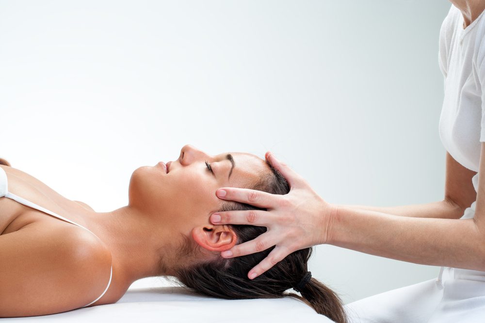 therapist doing healing osteopathic treatment on woman.